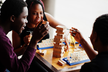 Group of three african american friends play table games.