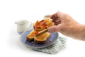 a hand picking up a slice of  peanut butter and jam on toast isolated on white
