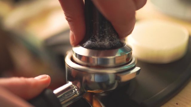 Slow motion of the process of making coffee step by step. Barista hands tamping freshly ground coffee beans 