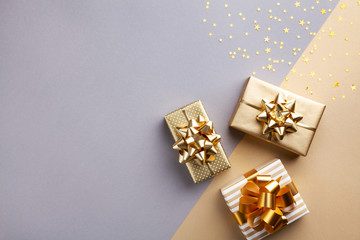 Golden gift or present boxes with golden bows and star confetti top view. Christmas background. Flat lay. - obrazy, fototapety, plakaty