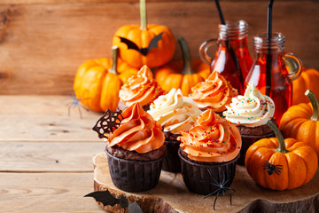 Halloween cupcakes and pumpkins on wooden background. Sweets for holiday party.