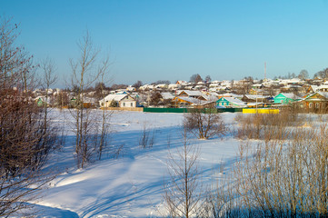 Winter landscape with village on background blue sky