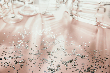 Shadows from glassware lay on a pink background with scattered silver sparkles. Holiday concept