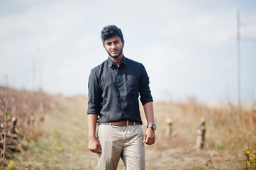 Indian man at black shirt and beige pants posed at field.