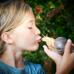 Portrait of preteen adorable child girl playing with her pet giant African snail (Achatina fulica). Concept of not to be afraid of unusual animals. Selective focus © Petr Bonek