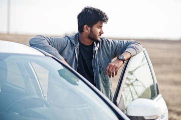 Indian man at casual wear posed near white car.