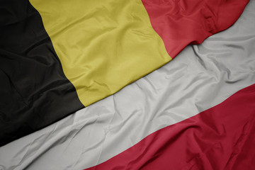 waving colorful flag of poland and national flag of belgium.