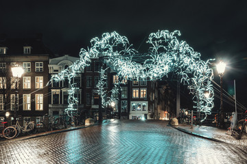 Giant spider of white light above a bridge over the Herengracht in the old town of Amsterdam