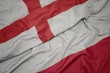 waving colorful flag of poland and national flag of england.