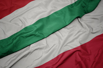 waving colorful flag of poland and national flag of hungary.