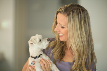 Portrait of a woman hugging and smiling at her dog.