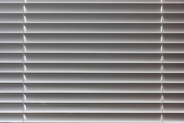 Background image of horizontally placed, plastic blinds on a Sunny window.