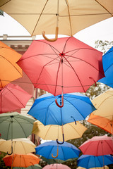 Texture. Lots of umbrellas hanging against the sky. Protection from sun and rain. Red, orange and blue.