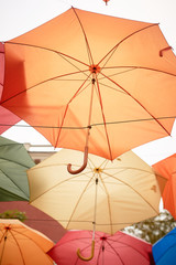 Texture. Lots of umbrellas hanging against the sky. Protection from sun and rain. Red, orange and blue.