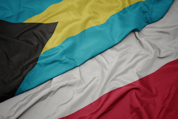 waving colorful flag of poland and national flag of bahamas.