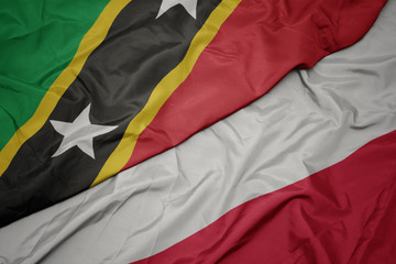waving colorful flag of poland and national flag of saint kitts and nevis.