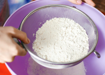 Woman lour sifting through a sieve for a baking, close up