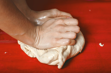 female hands in flour closeup kneading dough on table, close up