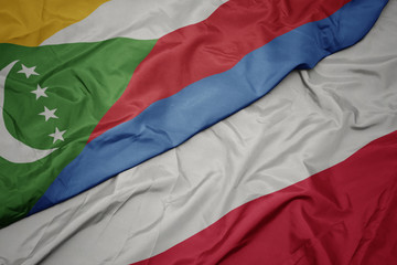 waving colorful flag of poland and national flag of comoros.