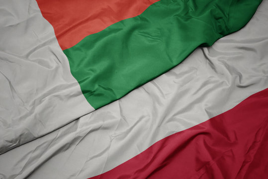 waving colorful flag of poland and national flag of madagascar.