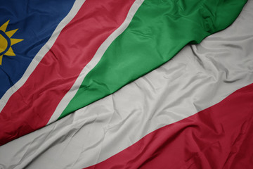 waving colorful flag of poland and national flag of namibia.