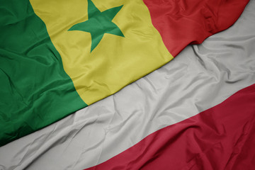 waving colorful flag of poland and national flag of senegal.