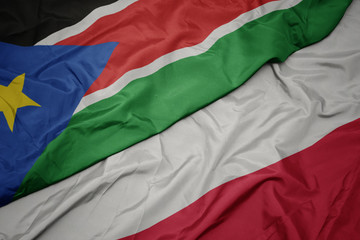waving colorful flag of poland and national flag of south sudan.