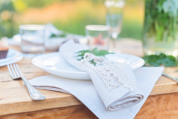 Table with plate is decorated with linen napkins and green leaf