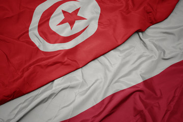 waving colorful flag of poland and national flag of tunisia.