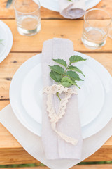 Table with plate is decorated with linen napkins and green leaf