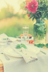 Table with plate is decorated with linen napkins and green leaf toned