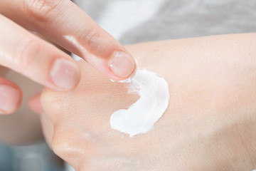 A close up and dorsal view on the hand of a healthy young caucasian woman, applying health and...