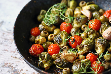 Baked Brussels sprouts in a pan with cherry tomatoes, garlic and olives. Vegan food. Diet concept. Autumn food.