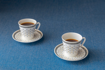 Two cups of coffee on blue background