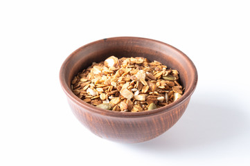 Clay bowl with granola. Granola in a brown plate.