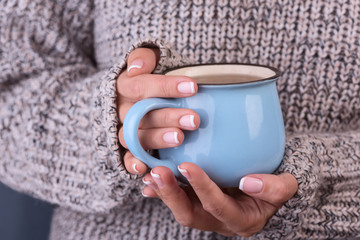 Сup of hot coffe in female hands in sweater close up