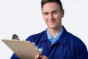 Studio Portrait Of Male Engineer With Clipboard And Spanner Against White Background