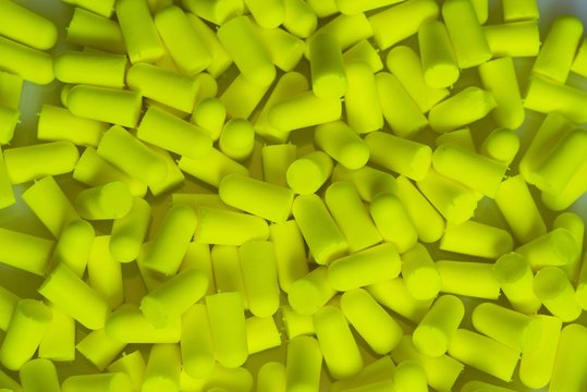 Greenish yellow Disposable earplugs memory foam background.