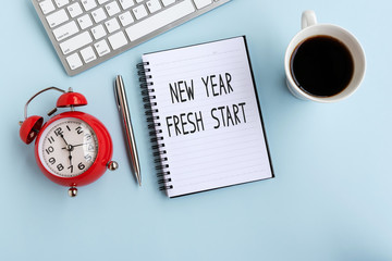 New Year Fresh Start text on note pad, flat lay office desk.