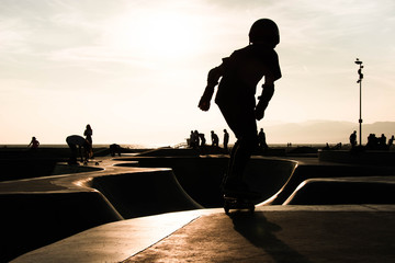 silhouette of young skater at sunset at venice beach skatepark