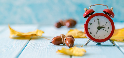 Autumn time change concept - red alarm clock on wood background, copy space