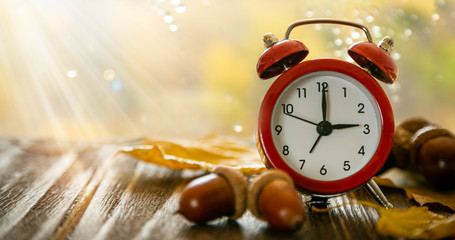 Autumn time change concept - red alarm clock on wood background, copy space