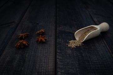 Anise stars and scoop of anise on a dark wooden table. The concept of using spices for dishes, enriching the taste.