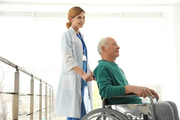 Obraz premium Nurse assisting elderly man in wheelchair indoors