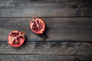 Pomegranate fruit on a dark wooden background and a cut pomegranate. The concept of eating and eating meals. Eating fruit, providing vitamins.