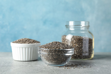 Glass and ceramic tableware with seeds on grey table, copy space