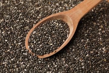 Chia seeds and wooden spoon textured background, close up