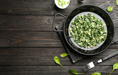 Flat lay composition with tasty spinach and space for text on black wooden table. Healthy food