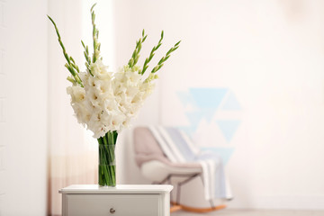 Vase with beautiful white gladiolus flowers on drawer chest in room, space for text