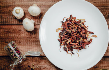 Fried Champignon on a wooden table. The concept of eating mushrooms, frying. Serving mushrooms with onions, side dishes. Tasty dishes.